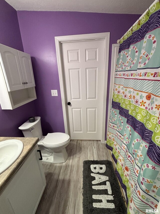 bathroom featuring toilet, a textured ceiling, wood finished floors, and vanity