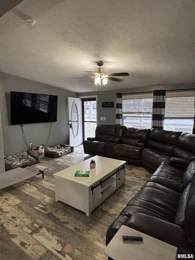 living area with a textured ceiling, dark wood finished floors, and a ceiling fan