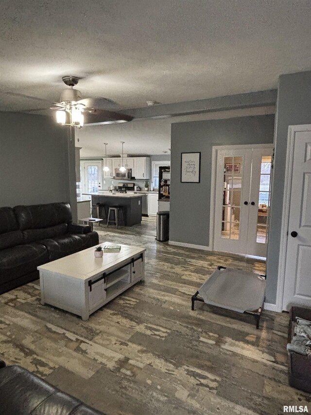 living area featuring dark wood-type flooring, ceiling fan, a textured ceiling, and baseboards