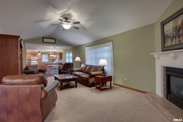 living room featuring light carpet, baseboards, lofted ceiling, a fireplace, and ceiling fan with notable chandelier