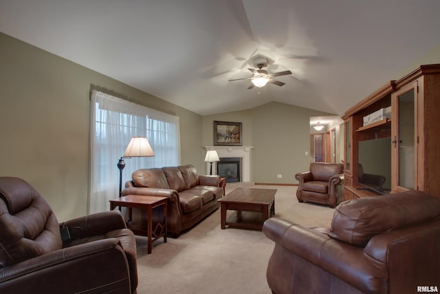 living area with light colored carpet, a glass covered fireplace, vaulted ceiling, ceiling fan, and baseboards