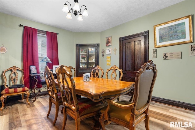 dining area featuring a notable chandelier, a textured ceiling, and wood finished floors