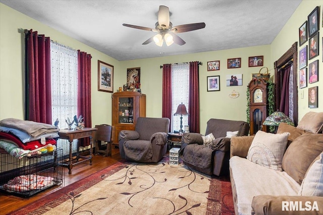 living area with ceiling fan, plenty of natural light, and wood finished floors