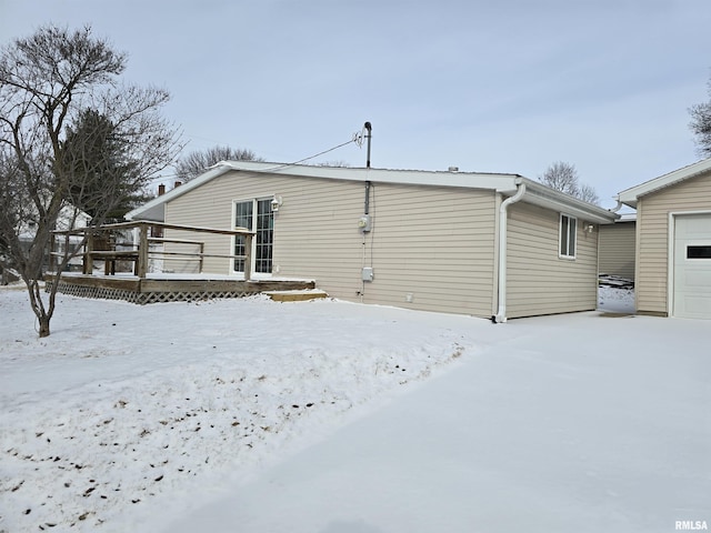 snow covered house with a garage and a wooden deck