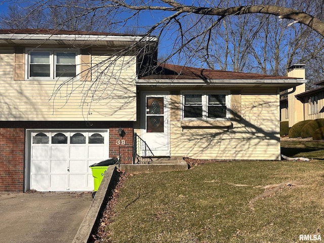 split level home featuring a front yard, brick siding, a chimney, and an attached garage