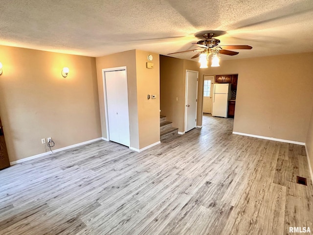 unfurnished room featuring a textured ceiling, stairway, wood finished floors, and baseboards