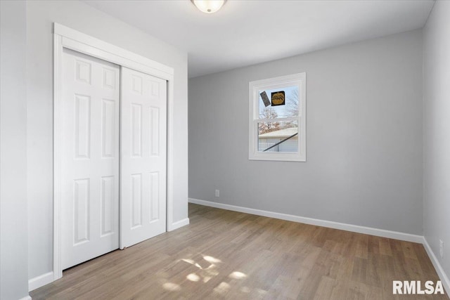 unfurnished bedroom with a closet, baseboards, and wood finished floors