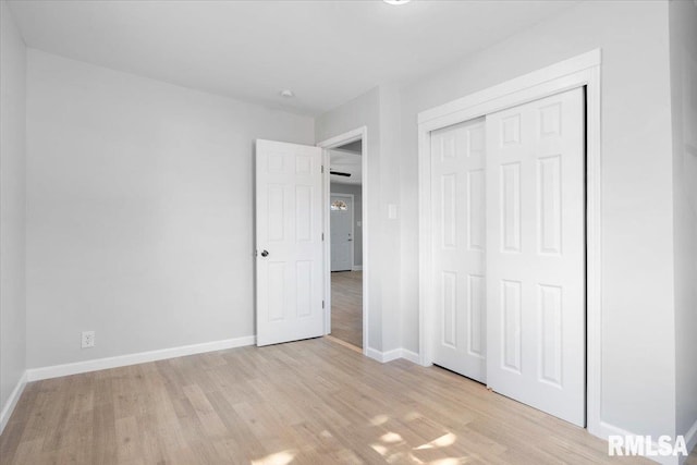 unfurnished bedroom with a closet, baseboards, and light wood finished floors