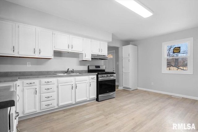 kitchen featuring light wood finished floors, stainless steel gas range oven, white cabinets, under cabinet range hood, and a sink