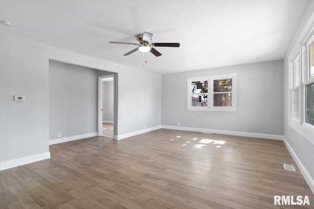 spare room with visible vents, wood finished floors, a ceiling fan, and baseboards