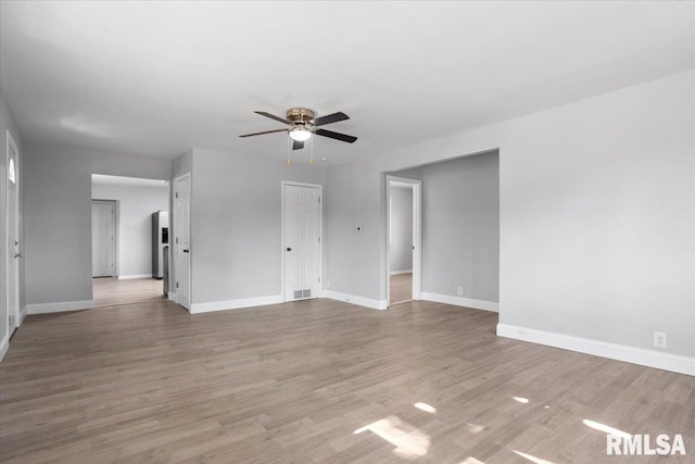 spare room featuring ceiling fan, baseboards, and wood finished floors