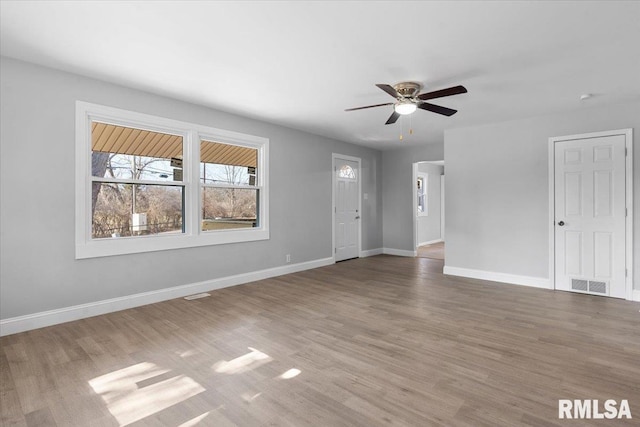 unfurnished living room featuring wood finished floors, visible vents, and baseboards