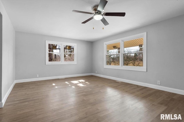 empty room with a ceiling fan, baseboards, and wood finished floors