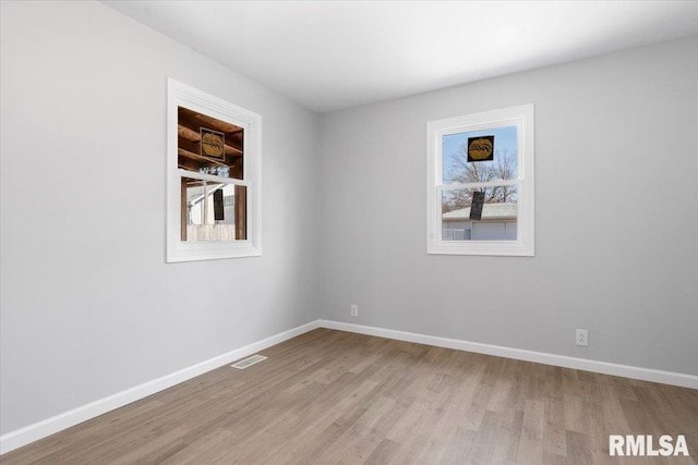 empty room with wood finished floors, visible vents, and baseboards