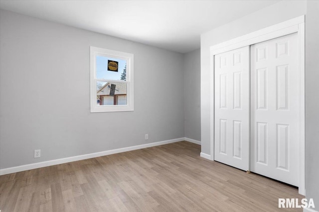 unfurnished bedroom with light wood finished floors, baseboards, and a closet