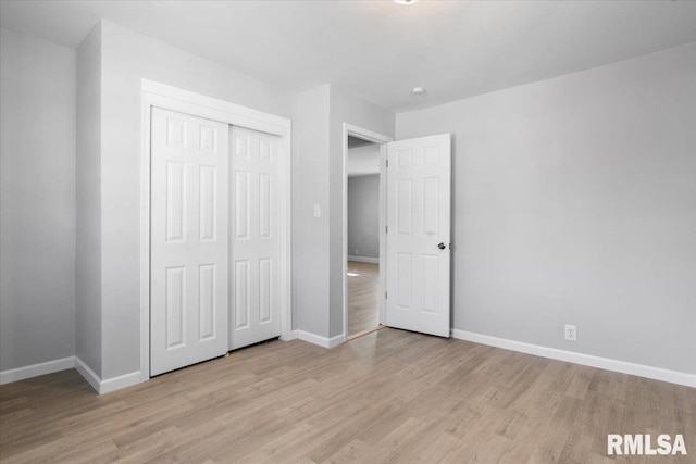 unfurnished bedroom with light wood finished floors, a closet, and baseboards