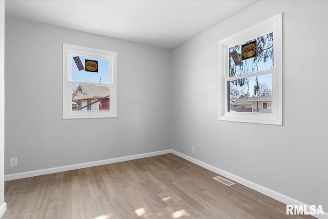 spare room featuring visible vents, baseboards, and wood finished floors