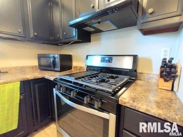 kitchen with under cabinet range hood and stainless steel gas range oven