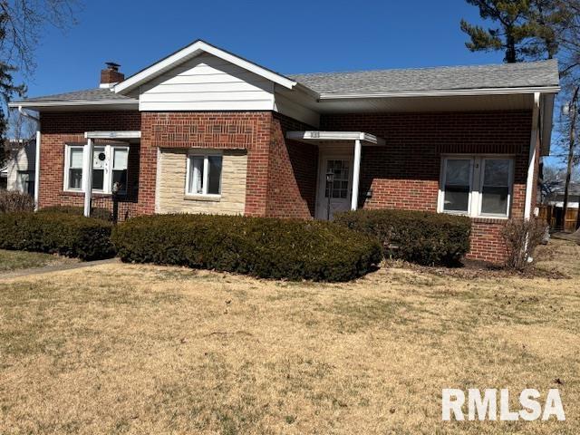 ranch-style home featuring brick siding, a chimney, and a front lawn