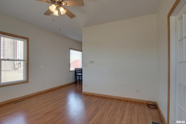 spare room with baseboards, ceiling fan, visible vents, and light wood finished floors