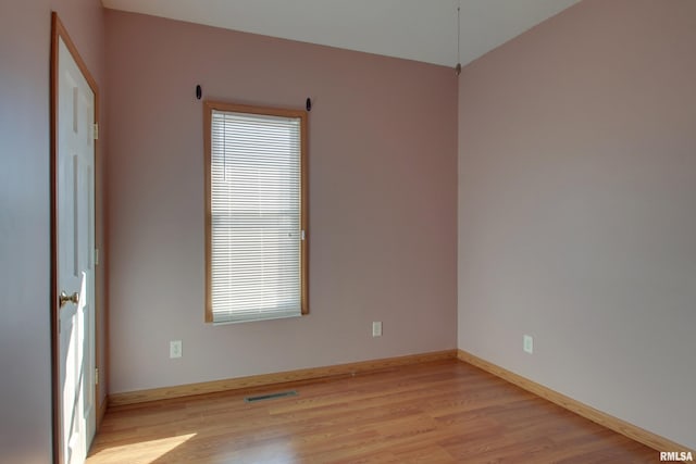 empty room with a healthy amount of sunlight, light wood-type flooring, visible vents, and baseboards