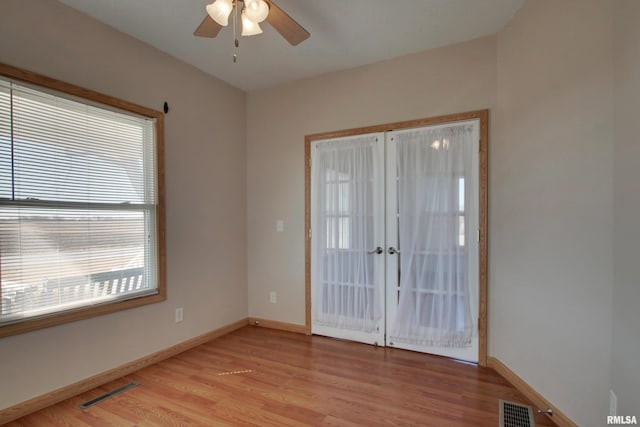 unfurnished room with light wood-style flooring, visible vents, baseboards, and french doors