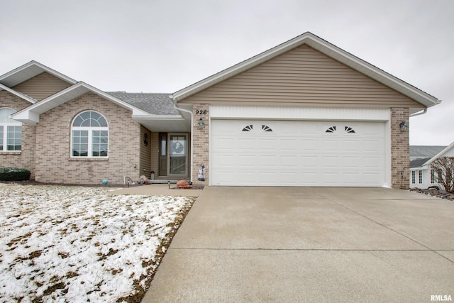 ranch-style home with a garage, brick siding, and driveway