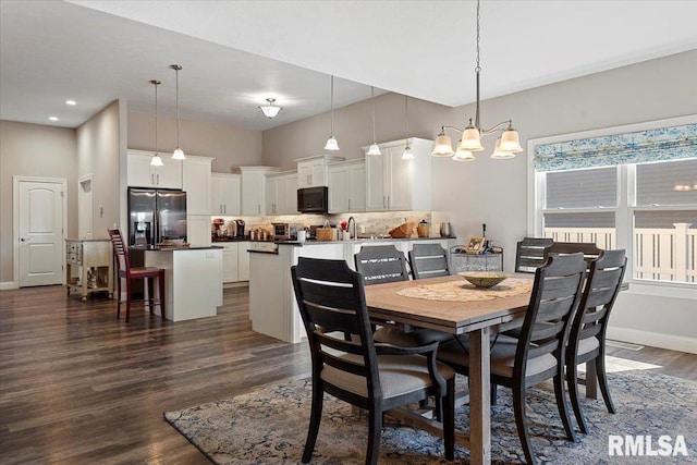 dining space with baseboards, a notable chandelier, dark wood finished floors, and a towering ceiling