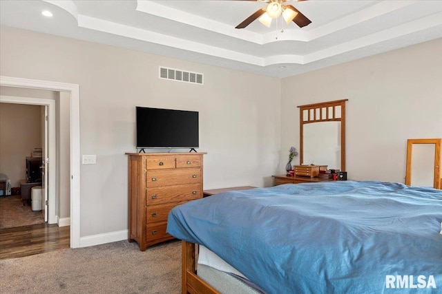 bedroom featuring visible vents, baseboards, a tray ceiling, and carpet floors