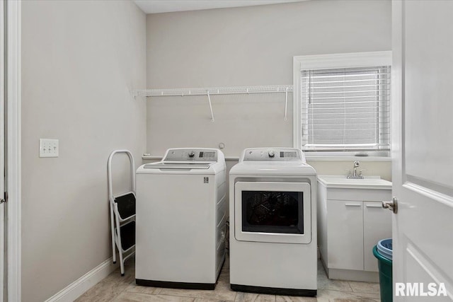 washroom with a sink, baseboards, cabinet space, and separate washer and dryer