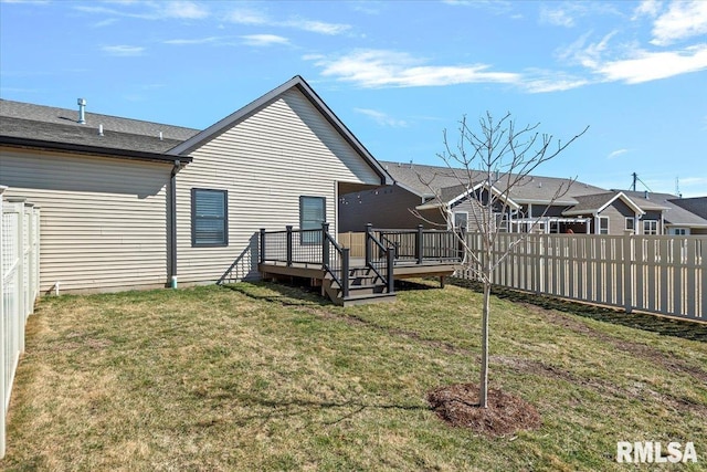 rear view of house with a lawn, a wooden deck, and fence