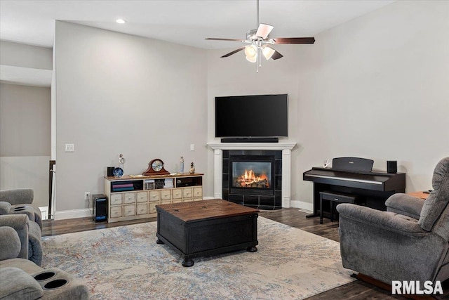 living room with a tiled fireplace, wood finished floors, baseboards, and a ceiling fan