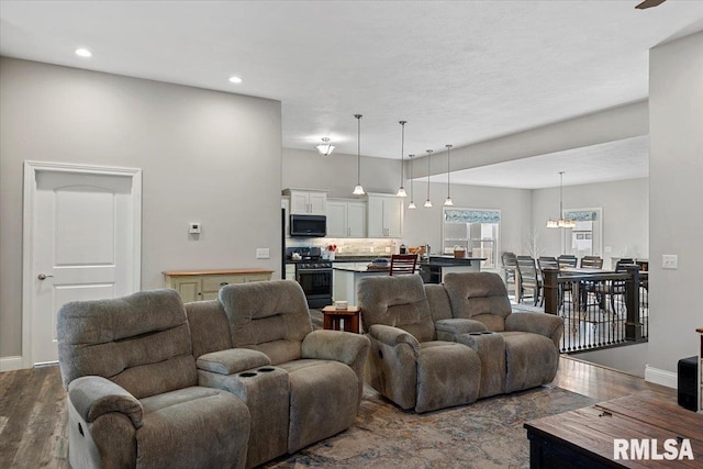 living area with recessed lighting, a notable chandelier, baseboards, and dark wood-type flooring