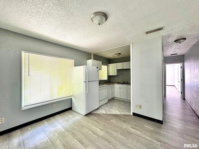 kitchen featuring white appliances, visible vents, baseboards, white cabinets, and light wood-type flooring