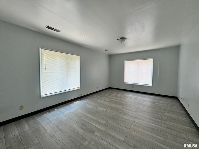 empty room featuring baseboards, visible vents, and wood finished floors