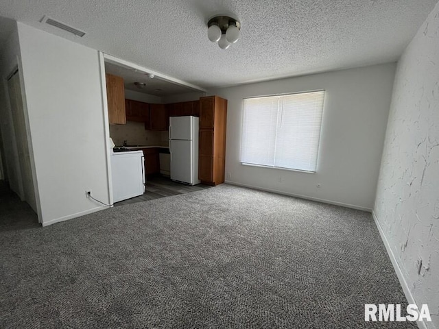 unfurnished living room featuring baseboards, visible vents, a textured wall, carpet, and a textured ceiling