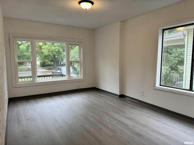 spare room with a textured ceiling, wood finished floors, and baseboards