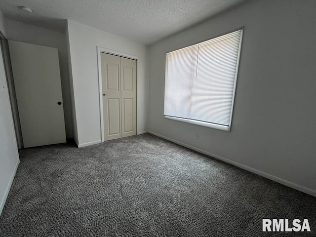 unfurnished bedroom with a textured ceiling, a closet, carpet flooring, and baseboards