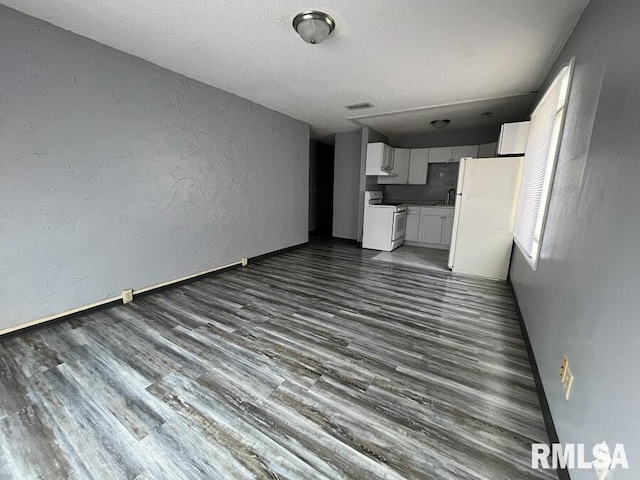 unfurnished living room featuring baseboards, visible vents, a textured wall, dark wood-style flooring, and a sink