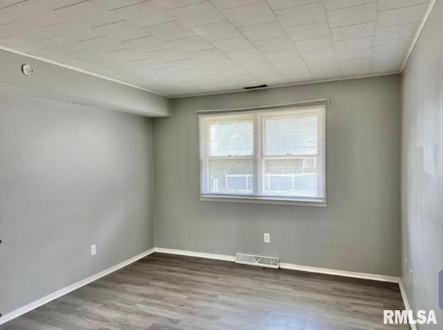 empty room with visible vents, baseboards, and wood finished floors