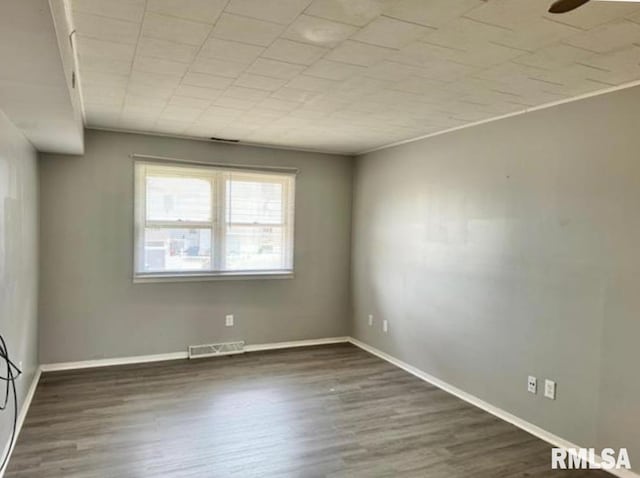 unfurnished room featuring baseboards, visible vents, and wood finished floors