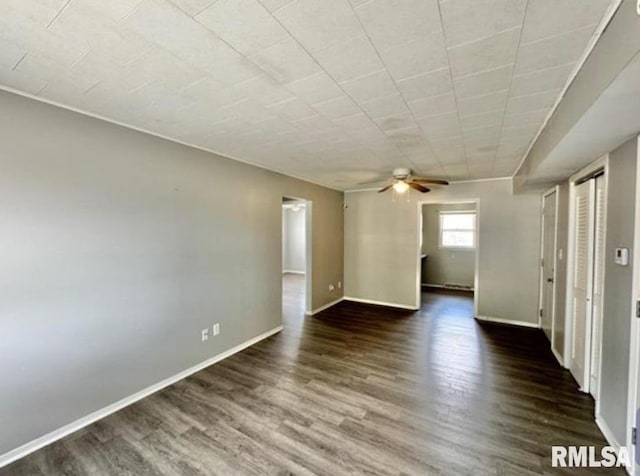 empty room featuring ceiling fan, dark wood finished floors, and baseboards