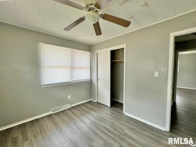 unfurnished bedroom featuring a closet, wood finished floors, visible vents, and baseboards