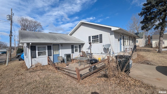 back of property with roof with shingles and central AC