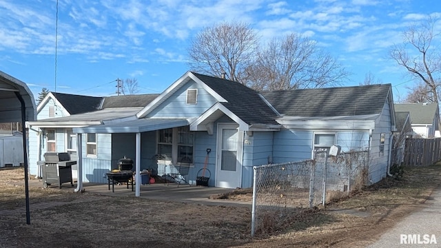 rear view of house featuring roof with shingles, a patio area, and fence