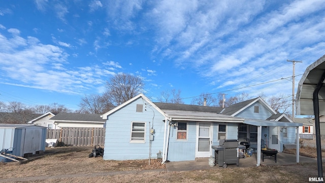 bungalow-style house with a storage shed, fence, a patio, and an outbuilding