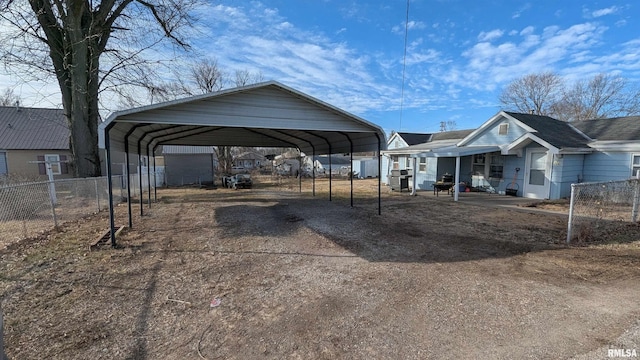 view of vehicle parking featuring dirt driveway, fence, and a carport