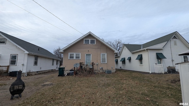 rear view of house featuring central AC unit and a lawn