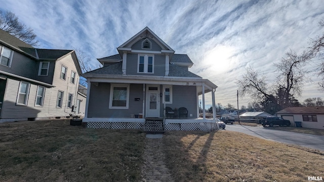 view of front of house with covered porch, a front lawn, and a shingled roof