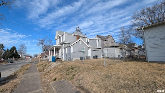 rear view of property featuring a lawn, cooling unit, fence, and a residential view